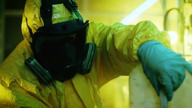In the Underground Drug Laboratory Clandestine Chemist Wearing Protective Mask and Coverall Mixes Chemicals. He Pours Liquid From Canister into Bowl, Toxic Compounds Create Smoke. 