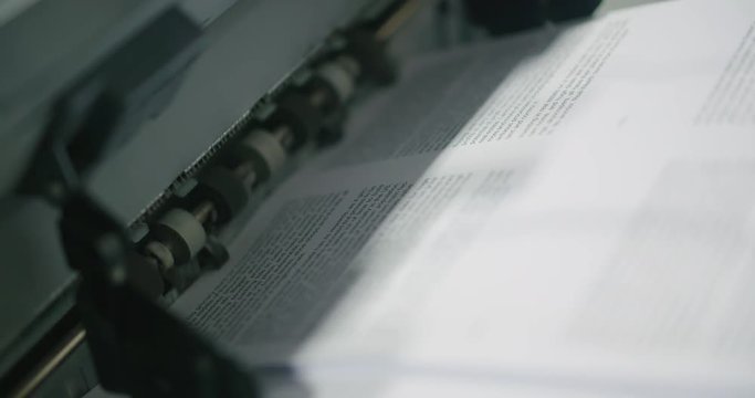 Book Paper Printing Machine Close Up Angle. a close up of paper printed and rolled out
