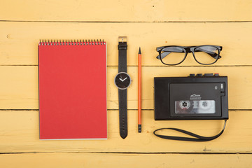 Journalist workplace - tape recorder, notepad on the yellowbackground, flat view