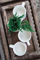 White ceramic mugs with pine tree on wooden trays