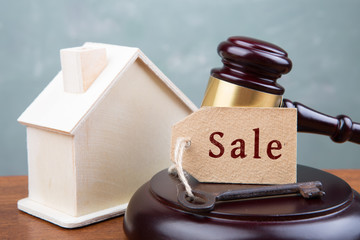 Real estate sale auction concept - gavel and house model on the wooden table