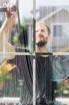 Window Washer Holding Squeegee Cleaning Outside Of Window Pane A