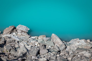 des rochers gris au bord de l'eau émeraude