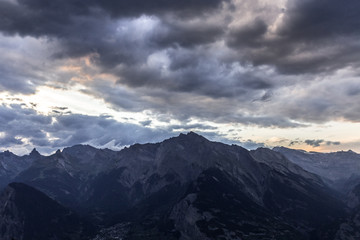 Fototapeta na wymiar Coucher de soleil violet sur des montagnes sombres avec des nuages 
