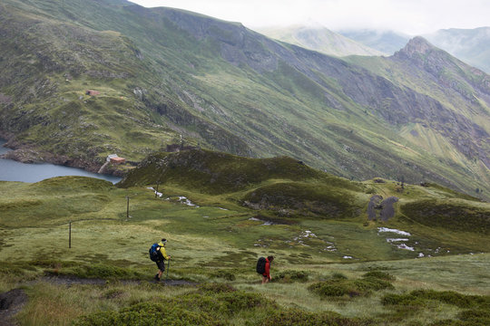 Two hikers going down on a mountain trail