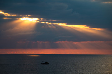 A magnificent seascape with dramatic clouds and sunlight, a boat floating in the sea