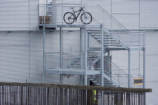 Fahrrad auf einer Stahltreppe vor einer Blechfassade 