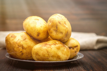 Raw potatoes on a brown wooden background