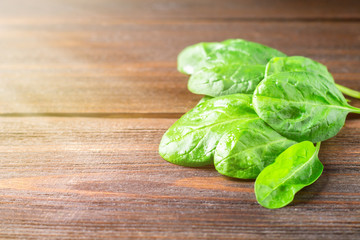 Green fresh spinach leaves on a wooden table