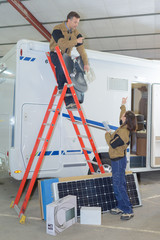 two electricians installing solar panels on rv roof