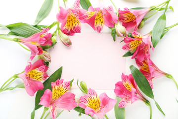 Pink alstroemeria flowers with sheet of paper on white background