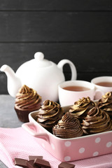 Tasty chocolate cupcakes in baking dish on grey background