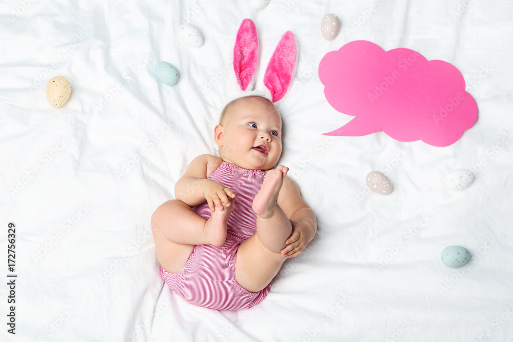 Wall mural little newborn baby with rabbit ears, eggs and speech bubble