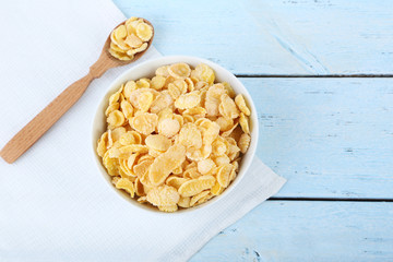 Cornflakes in bowl on blue wooden table