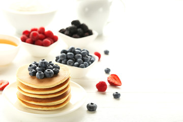 Tasty pancakes with blueberries on white wooden table