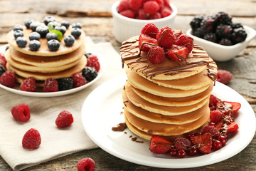 Tasty pancakes with berries and chocolate on wooden table