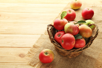 Ripe and sweet apples in basket on wooden table