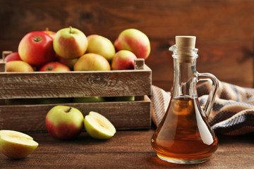 Apple vinegar in glass bottle on brown wooden table