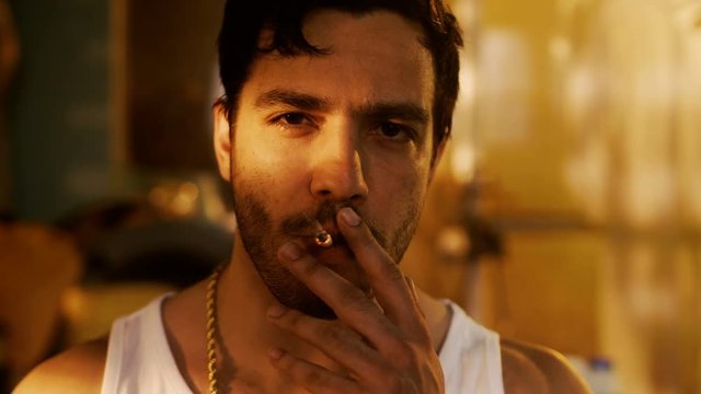Smoking Brutal Gang Member with Gold Chain Aggressively Looks into the Camera. 