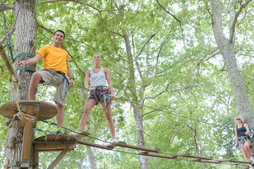 Naklejka na ściany i meble family on a rope climbing in the adventure park