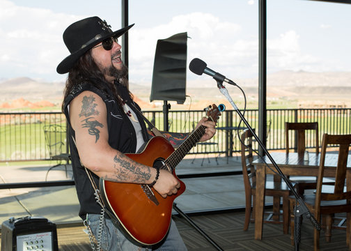 Musician playing guitar and singing at a local club with Sand Hollow Golf Course in the background