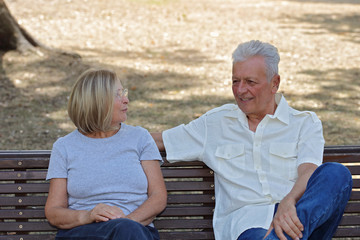 Old friends meeting. Senior man and woman sitting on bench in the park and talking. Active retirement concept