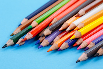 Fototapeta premium Color pencils on white background. Tools for drawing, education, school, creativity. Set of colored pencils on a blue background.
