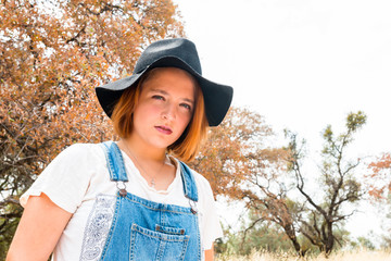 Girl With Red Hair, Overalls and Black Hat Standing in Field