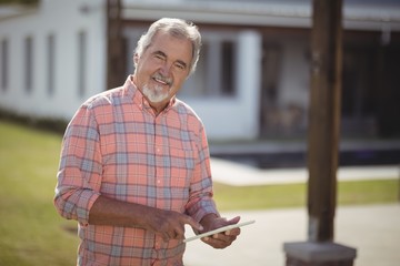 Smiling senior man using digital tablet