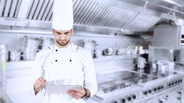 Caucasian chef using a digital tablet and showing OK sign while standing in the kitchen room
