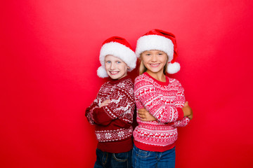 Fototapeta premium Small adorable charming relatives grin, bonding in traditional x mas knitted clothing, jeans, posing isolated on red background, excited, unity and togetherness. Holy time of the year!
