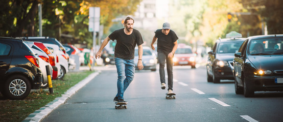 Two skateboarders riding skateboard slope on the city streets