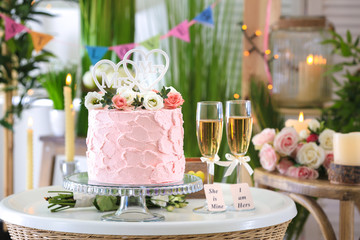 Beautiful cake for lesbian wedding decorated with flowers on table in the room