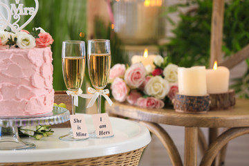 Two champagne glasses with cake on table in the room. Concept lesbian wedding