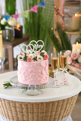 Beautiful cake for lesbian wedding decorated with flowers on table in the room