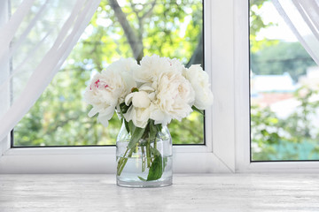 Vase with beautiful peony flowers on windowsill
