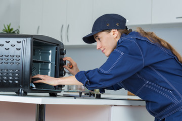 Fototapeta na wymiar woman worker repairing oven appliance in kitchen room
