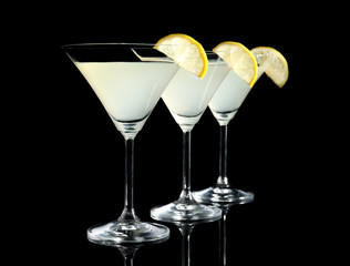 Glasses of lemon drop martini with slices of fruit on black background