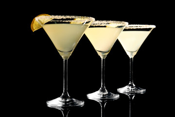 Glasses of lemon drop martini with slices of fruit on black background