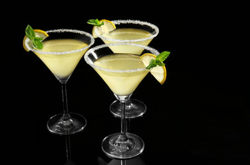 Glasses of lemon drop martini with slices of fruit on black background