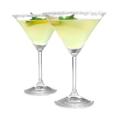 Glasses of lemon drop martini with slices of fruit on white background
