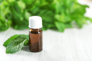 Bottle of essential oil and mint on wooden table