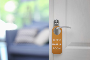Open door with sign PLEASE MAKE UP ROOM on handle at hotel