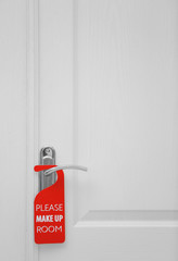 Naklejka premium Closed door with sign PLEASE MAKE UP ROOM on handle at hotel