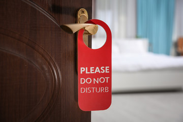 Open door with sign PLEASE DO NOT DISTURB on handle at hotel
