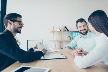 Side profile view of cheerful married couple, having consultation with a lawyer about a credit for buying purchase, all are dressed in formal outfits, smiling