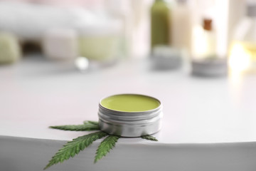 Jar with hemp lotion on white table
