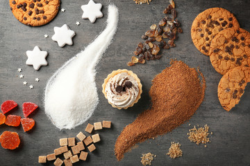 Composition made with variety of sweets, white and brown sugar on grey background