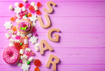 Sugar composition with variety of sweets on pink wooden background