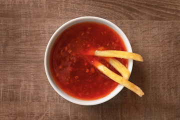 Chili sauce and french fries on wooden background